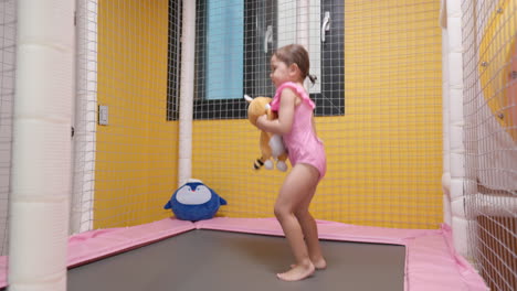 Niña-Pequeña-Alegre-Sonriente-Saltando-En-Trampolín-En-El-Patio-Interior---Cámara-Lenta