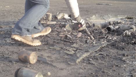 recoger latas de aluminio desechadas en el suelo después de un incendio.