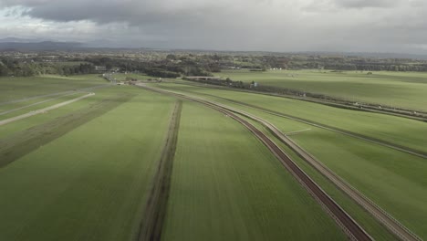 green aerial flyover of horse race track under overcast irish sky