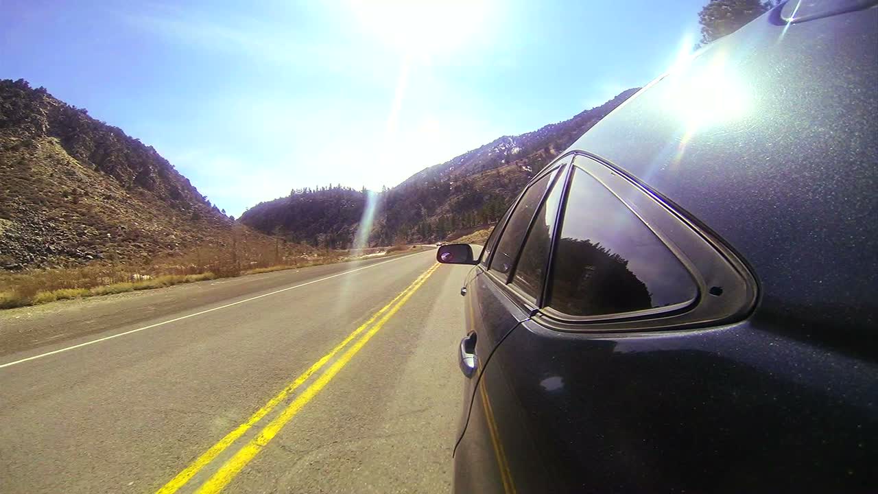 Ripresa in soggettiva mentre si guida velocemente lungo una strada di montagna con l'auto visibile
