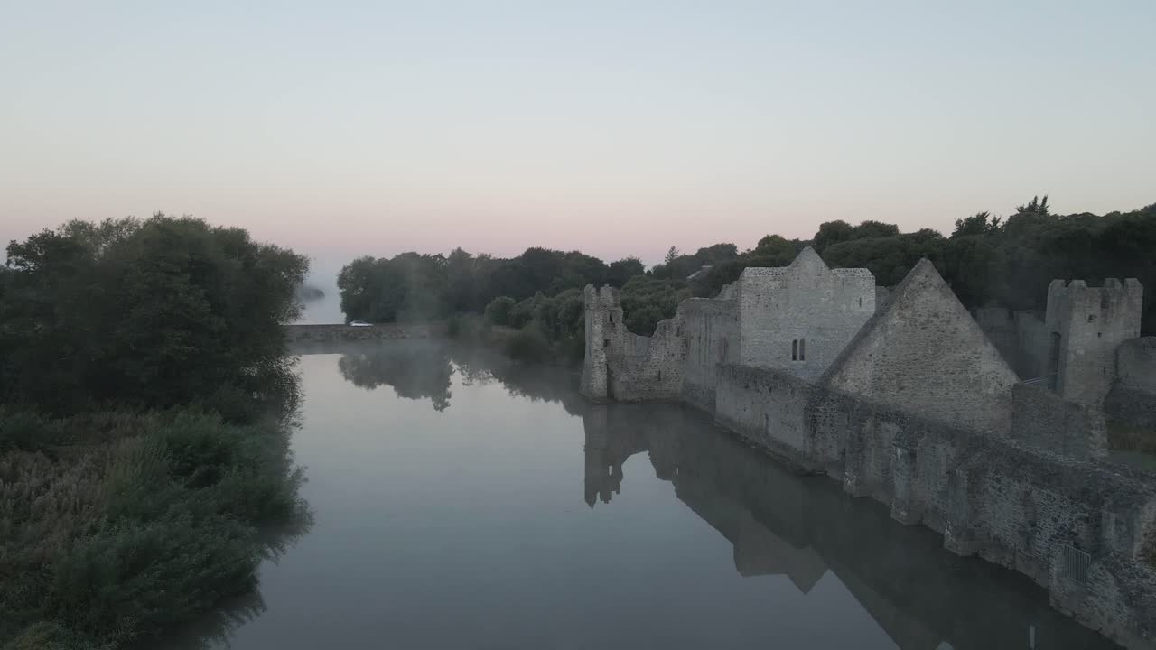 Adare Castle by a misty river at dawn with soft pastel skies in County Limerick Ireland