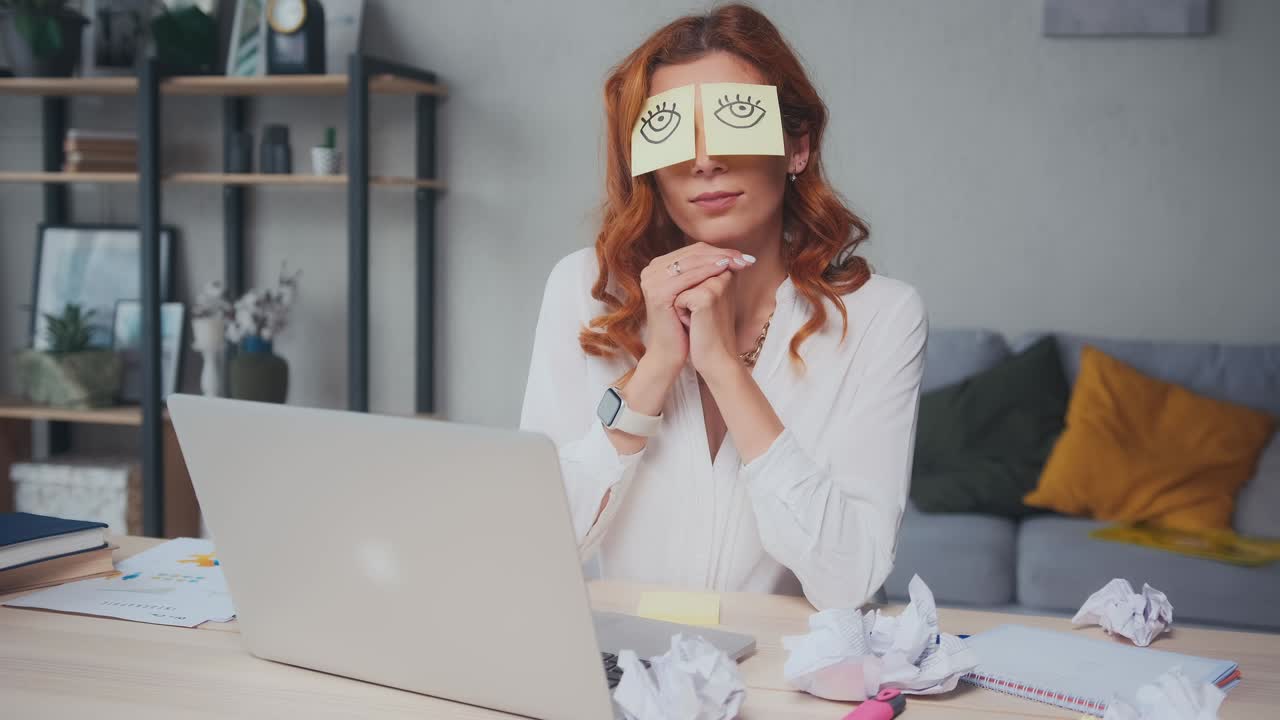 Tired caucasian woman napping sits at table with stickers on eyes