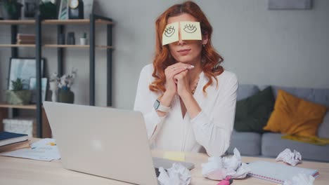 tired caucasian woman napping sits at table with stickers on eyes