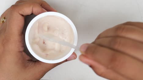 yogur fresco en un recipiente de plástico y una cuchara en la mesa
