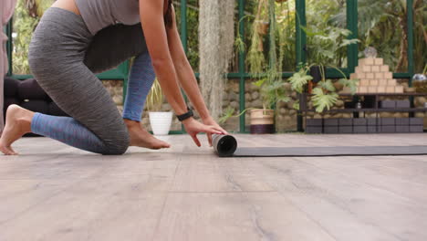 rolling out yoga mat, woman preparing for yoga session in glass house, copy space