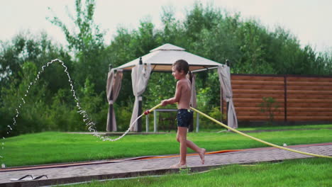 the two boys are playing with mom and dad in the backyard of their house drenching with hose water and laughing and smiling in slow motion. happy family