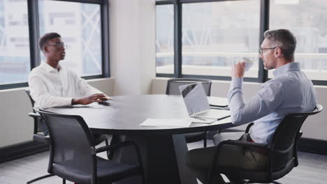 A-black-and-a-white-businessman-in-a-meeting-room-for-a-job-interview,-close-up,-selective-focus