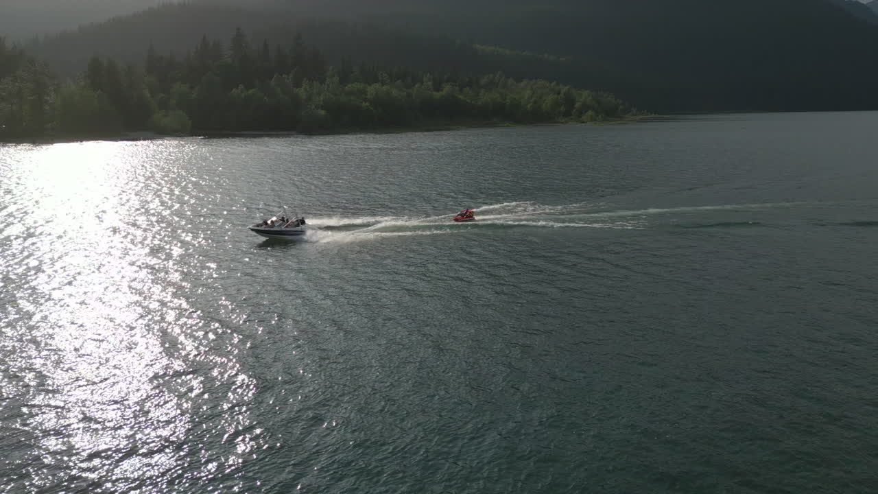 Aerial of speedboat pulling people in floaty device on British Columbia Lake