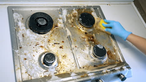 effectively cleaning a stove. hand with a sponge scrubbing a greasy kitchen stove covered in dirt and residue, showcasing the effort in cleaning