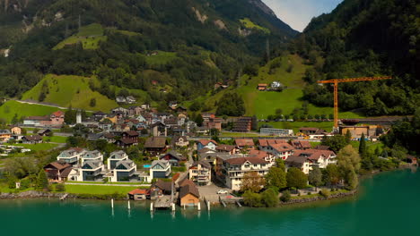 aerial shot of the lakeside village sisikon embedded into a hilly and rocky landscape located at lake lucerne on a sunny summer day. train passing by