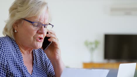 senior woman talking on mobile phone in living room 4k