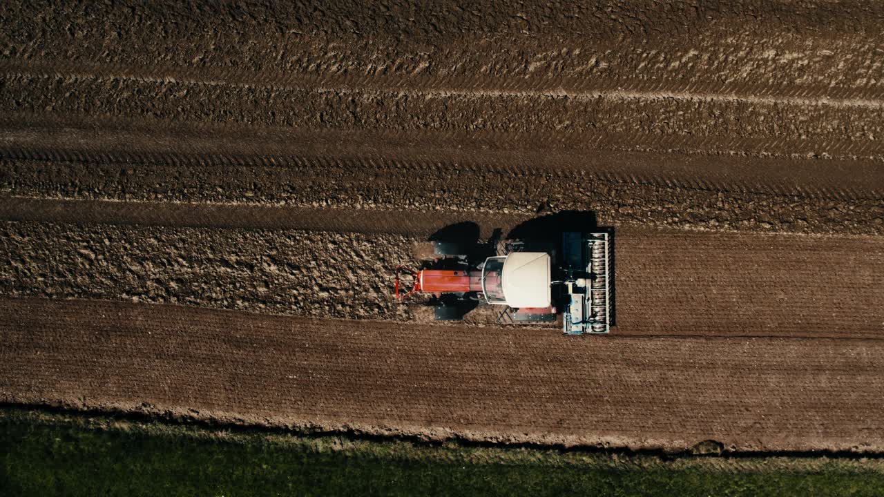 Aerial shot of a lone tractor plowing fertile fields at sunset