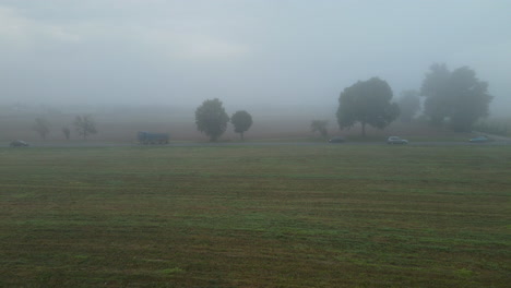 Reisende-Fahrzeuge-über-Nebeligem-Himmel-Auf-Landschaftsfeldern-In-Lubawa,-Polen