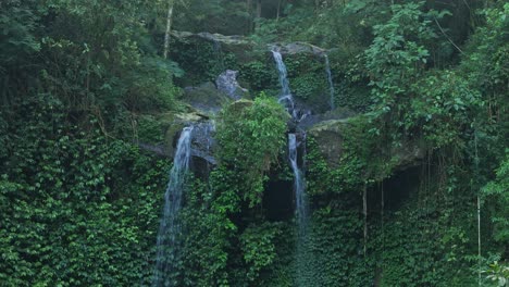 drone flying forward to natural waterfall cascade in the heart of a dense jungle