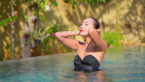 beautiful exotic woman in infinity swimming pool on tropical destination, slow motion