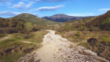 Aerial-pull-back-over-dry-river-surrounded-by-mountains