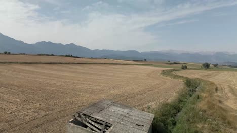 Drohne-Fliegt-über-Dem-Ackerland-Mit-Den-Bergen-Am-Horizont