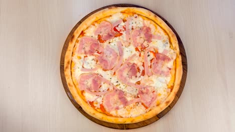 pizza con tocino y queso en una tabla de madera en la mesa. vista de cerca de arriba.