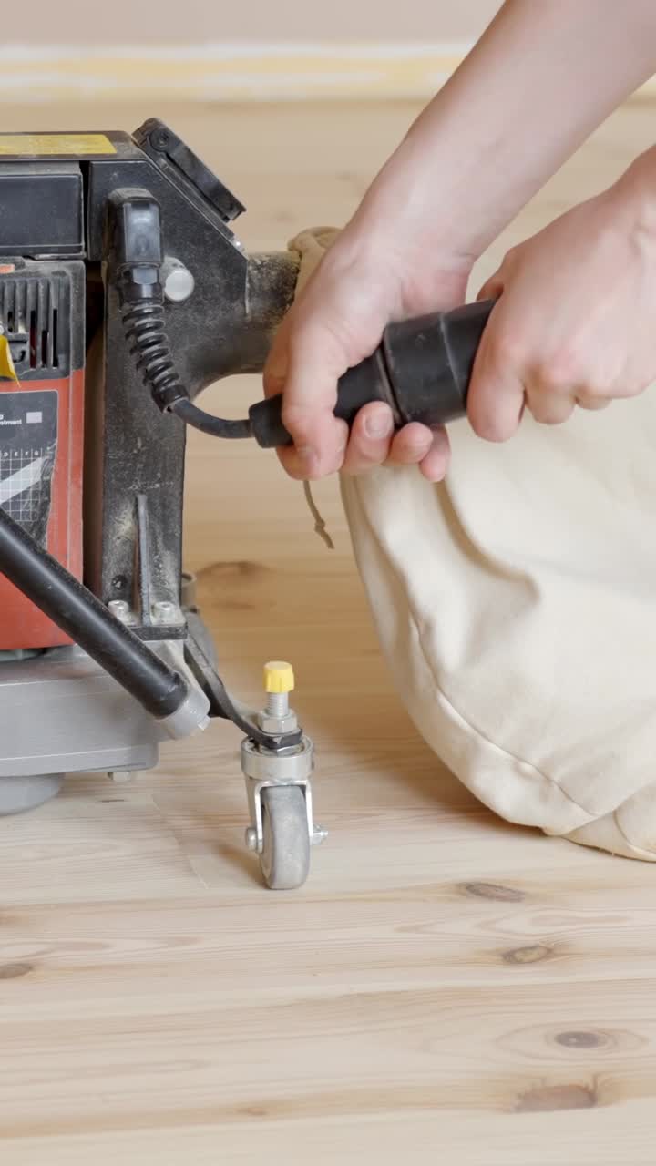 Close-up of a sanding machine with a dust collector, working on wood floor edges