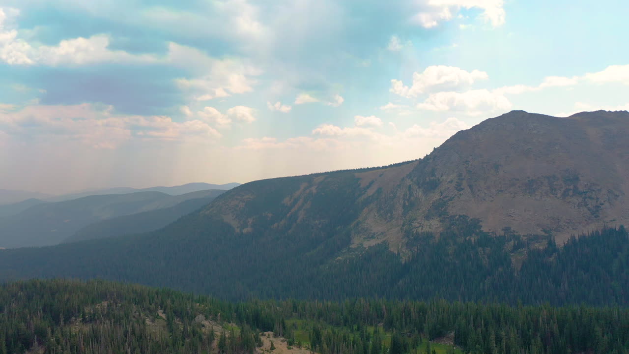 Aerial Drone Footage of Nederland Colorado Mountains Covered in Thick Pine Tree Forest with Clouds Casting Shadows during Summer in the Rocky Mountains