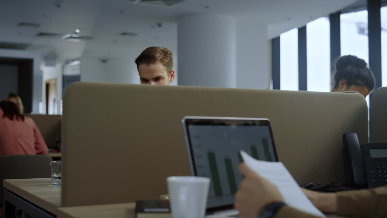 Fokusert forretningsmann bruker bærbar PC på arbeidsplassen. Fagperson holder dokumenter.