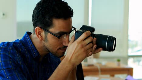 Male-graphic-designer-using-digital-camera-at-his-desk