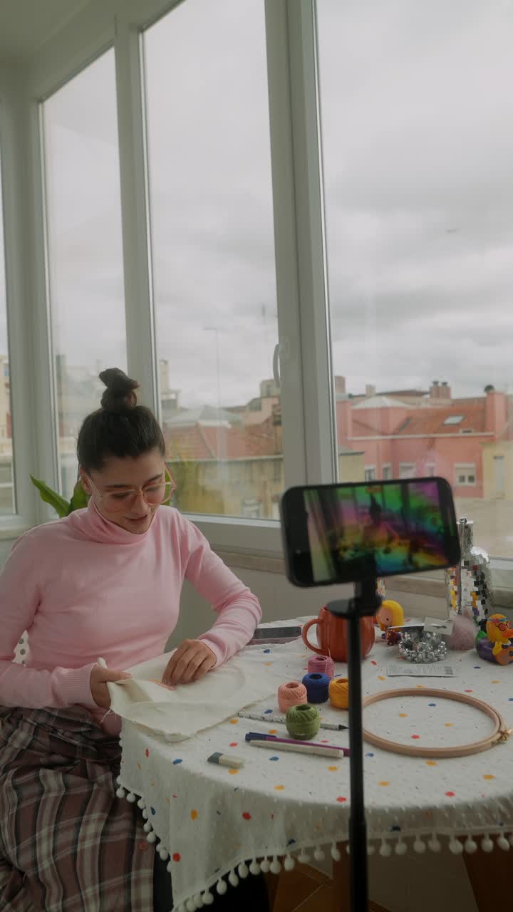 Giovane donna che registra un tutorial di artigianato con lo smartphone a casa