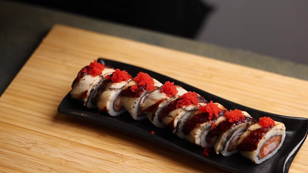 Koch dekoriert Sushi-Rollen mit rotem Tobiko-Rogen