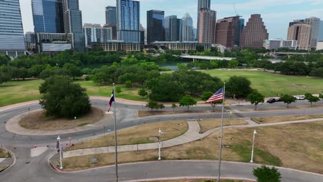 Banderas-De-Estados-Unidos-Y-Texas-Ondean-En-Austin,-Brisa-De-Texas-Frente-Al-Horizonte-De-La-Ciudad