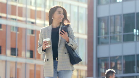 Businesswoman-With-Takeaway-Coffee-Walking-To-Office-Following-Directions-On-At-Mobile-Phone-App