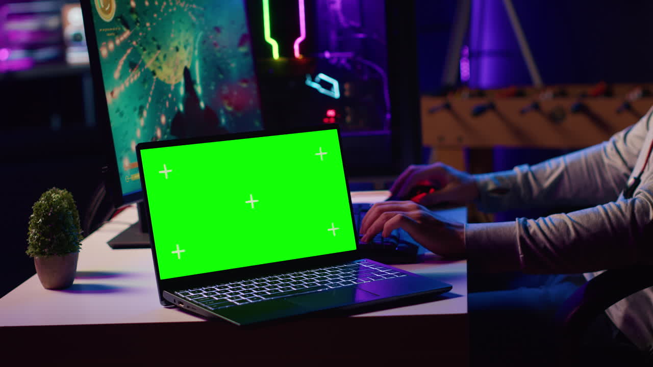 laptop con schermo verde accanto all'uomo che gioca con gli amici online in un gioco di volo spaziale