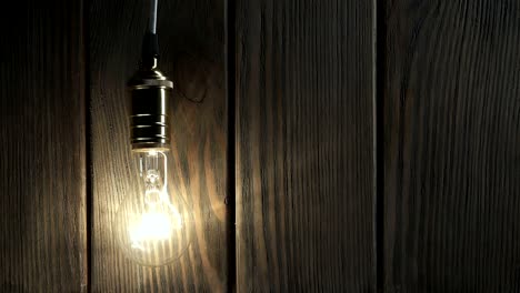 the light bulb slowly lights up, quickly flickers on a background from a wood