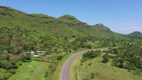 Una-Toma-De-Drones-De-Hermosas-Tierras-De-Cultivo-Verdes-Con-Colinas-A-Un-Lado-Y-Una-Carretera-En-El-Medio-Del-Cuadro