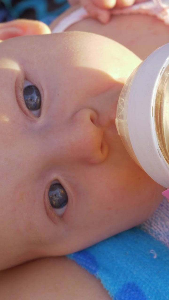 Bambino sdraiato in grembo alla madre che beve dal biberon