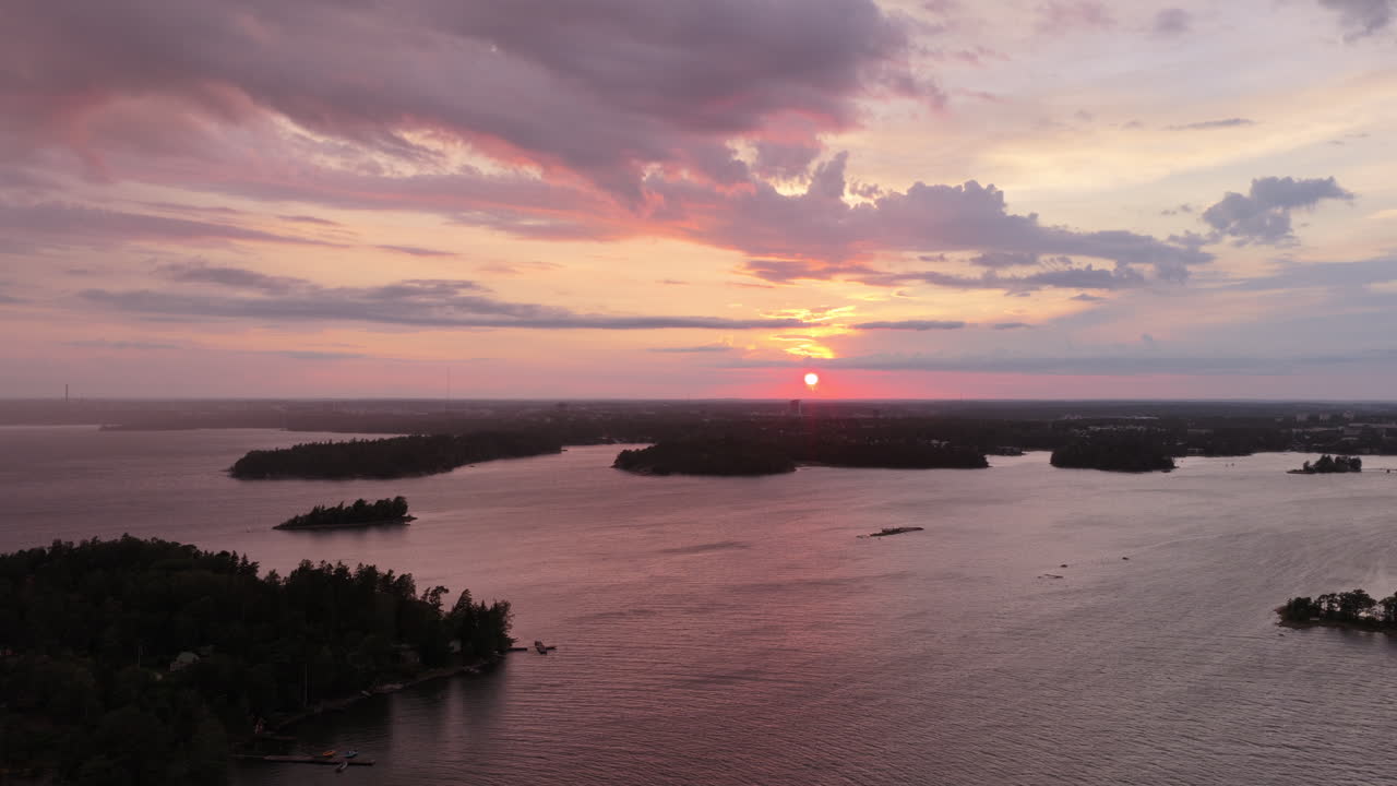 Drone flying sideways in front of silhouette islands of the finnish archipelago