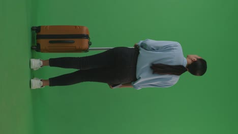 full body of back view asian woman traveler with luggage walking and standing in the green screen background studio, during sunset time