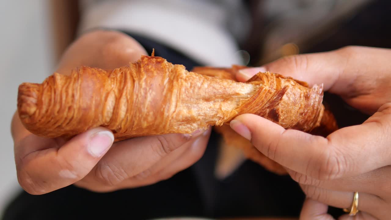 Close-up of a croissant being torn apart
