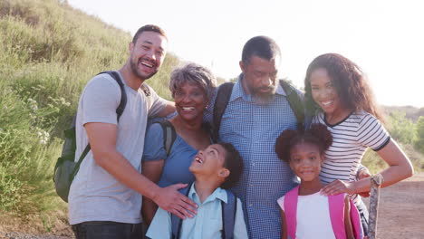 slow motion portrait of multi generation family wearing backpacks hiking in countryside together