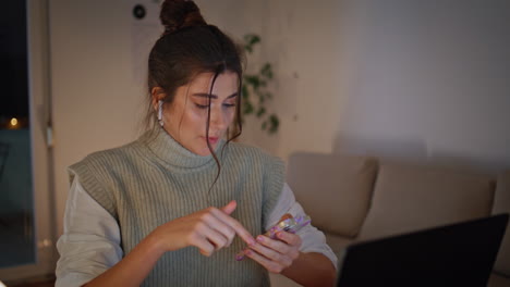 mujer que llama a través de una videoconferencia comprobando el contenido en su teléfono inteligente en el lugar de trabajo