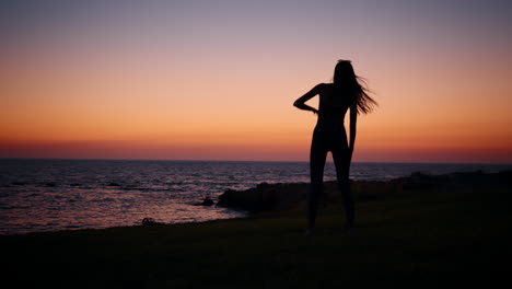 mujer estirándose en la playa del atardecer