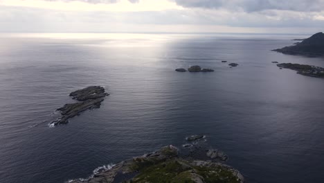 Aerial-sunset-over-the-Norwegian-sea-from-rocky-Reine-village-coast,-Norway