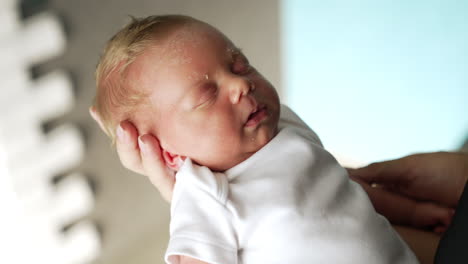 beautiful blond baby sleeping on mom's hand. newborn sleeping tight waved by his mother. close up.