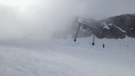 Aerial-view-showing-Skier-pulled-by-ski-lift-during-cloudy-and-snowy-day-in-Austrian-alps