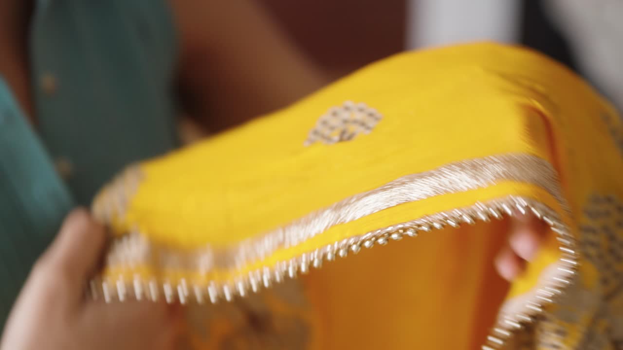 Ung sørasiatisk kvinne bretter gult indisk sjal, Dupatta