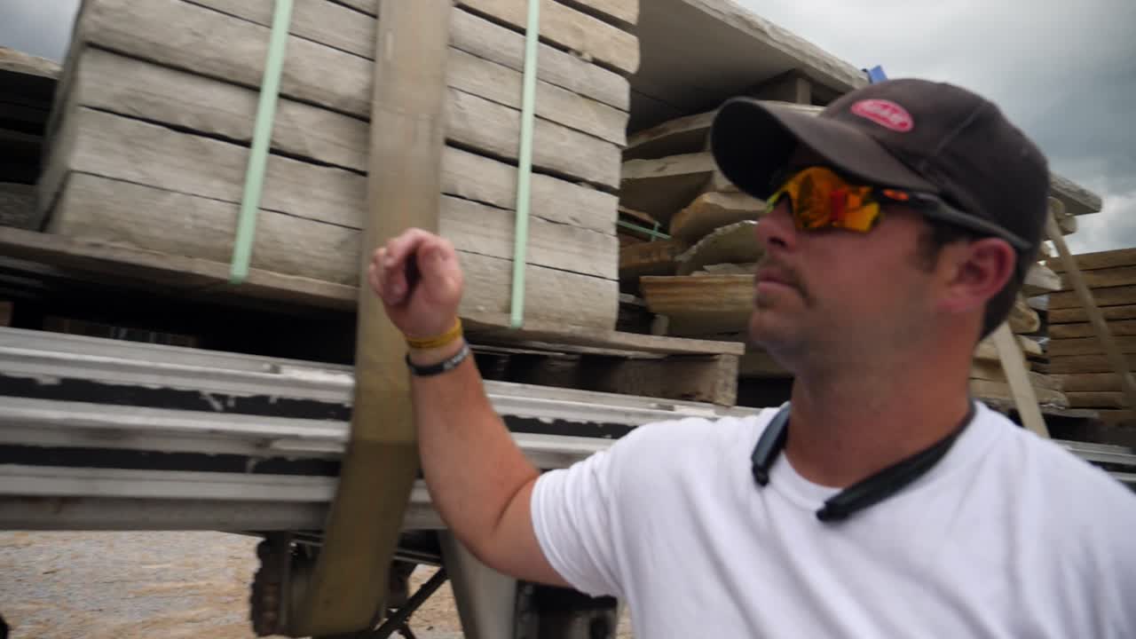 camionero comprueba la carga de piedra en el remolque del tractor