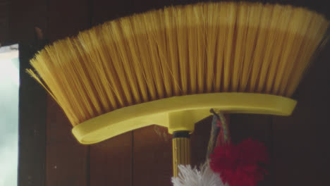 close-up of a yellow broom hanging on a wall