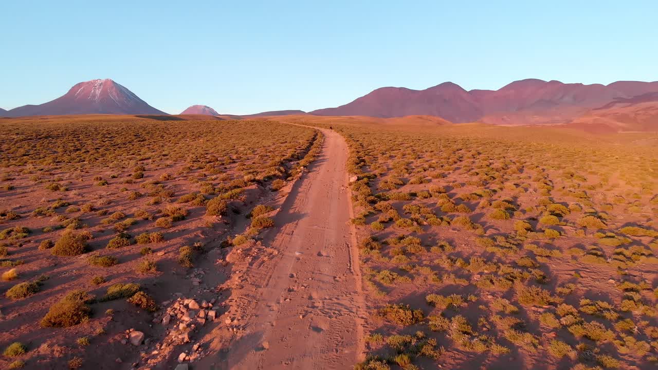 toma aérea de un viajero solitario en un camino de tierra al atardecer en el desierto de atacama, chile, sudamérica