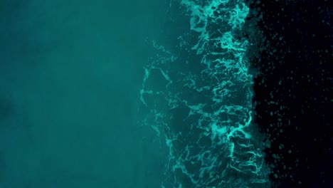 turquoise blue sea with waves splashing on the shore - aerial drone, top-down shot