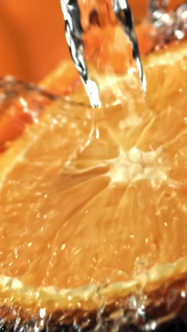 Acqua rinfrescante che schizza su una fetta d'arancia succosa al rallentatore
