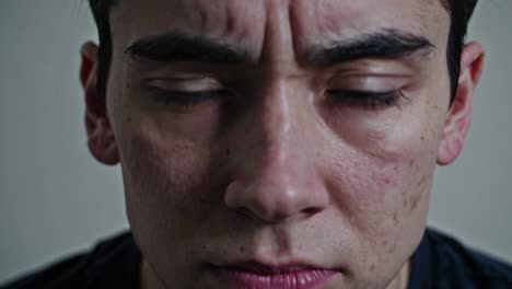 intense close-up captures raw emotions of a young man during a deep moment of reflection in a muted interior setting